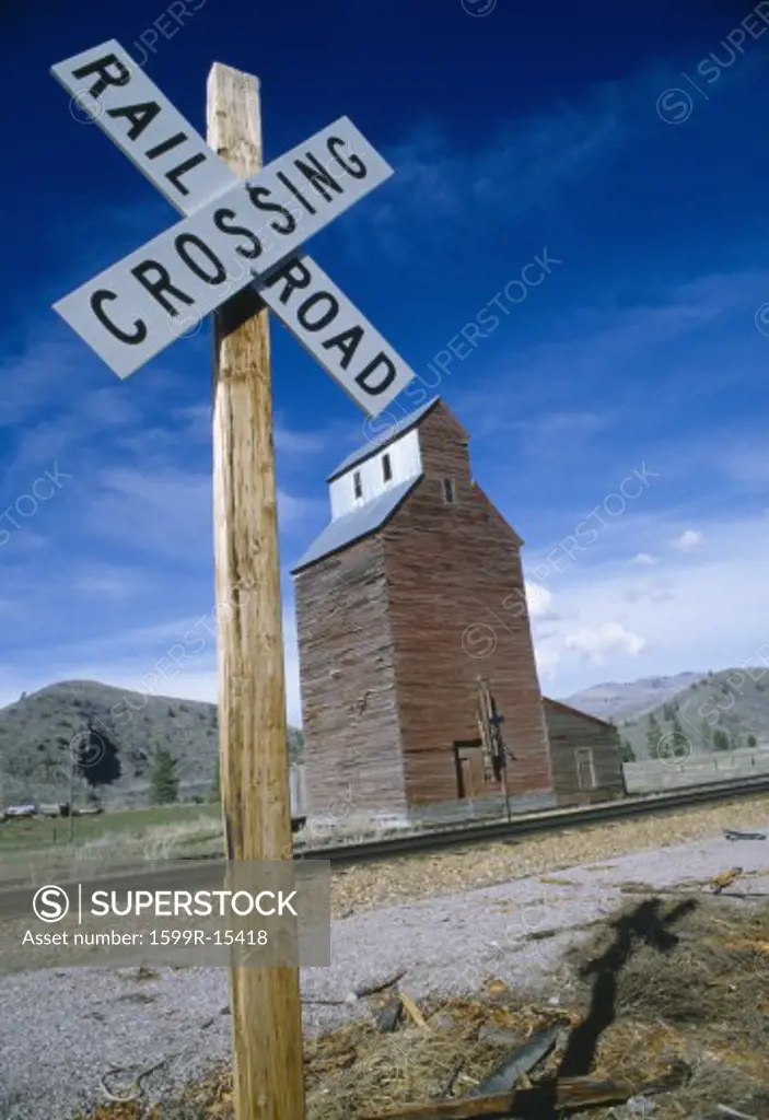 Railroad crossing sign with grain silo in background, Montana