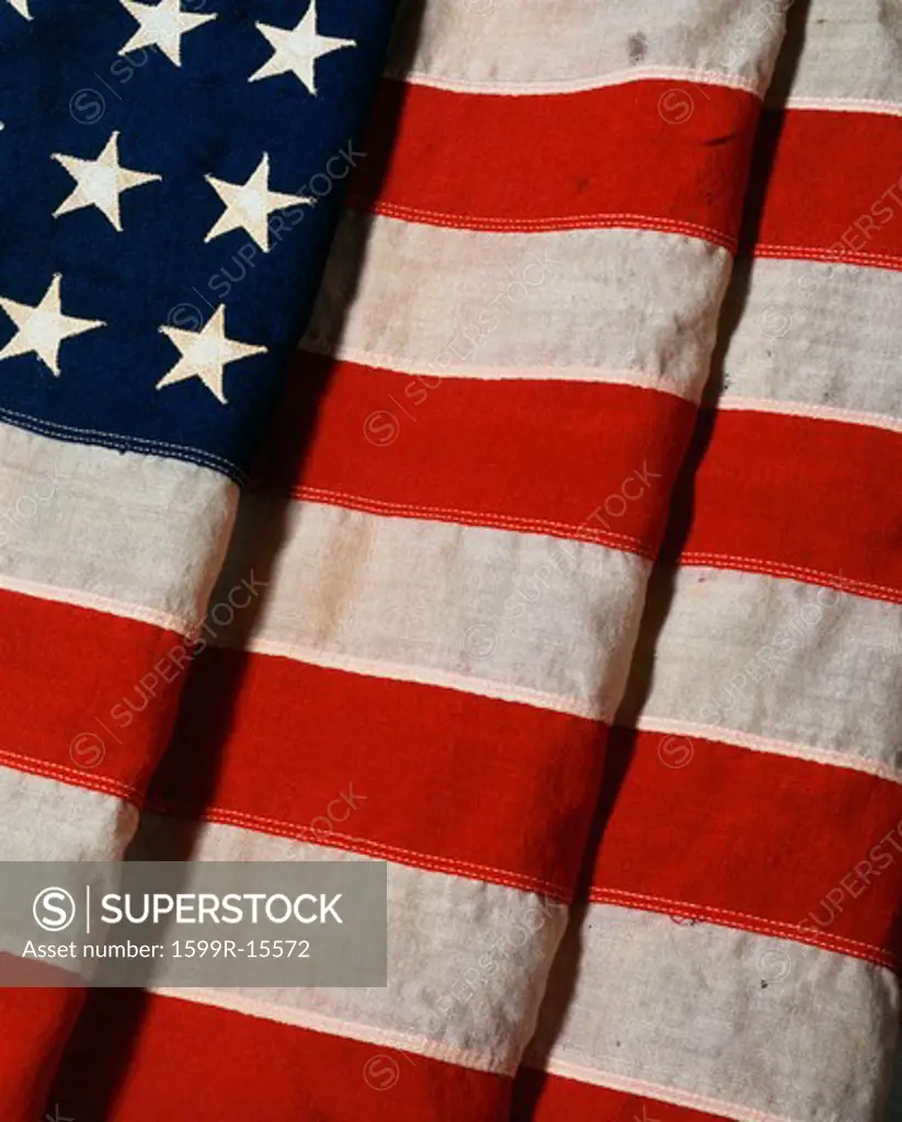 This is a vertical view of a folded American flag. It is a vintage flag with 48 stars. It is folded twice with one fold cutting into the field of stars and the other three quarters into the red and white stripes.