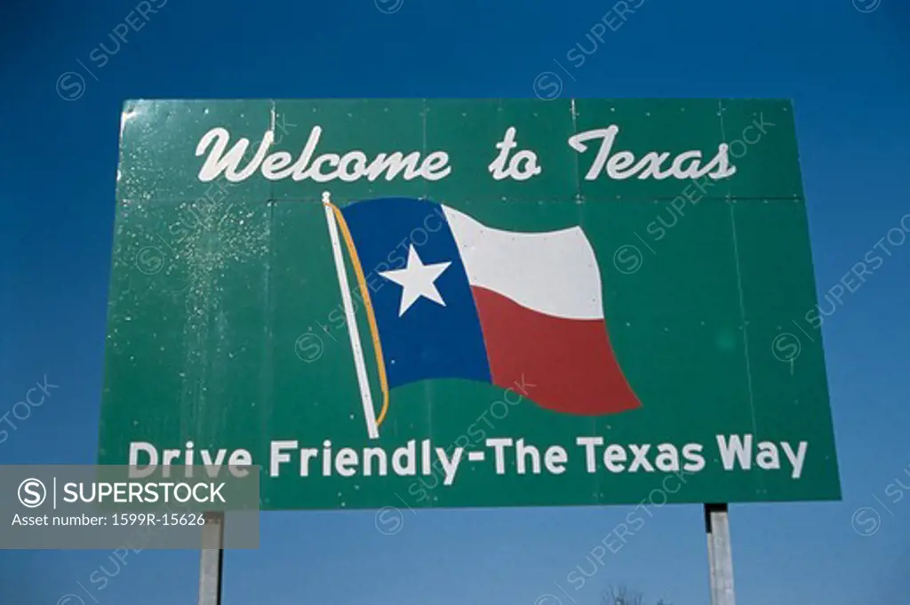 This is a road sign that says, Welcome to Texas, drive friendly, the Texas way. It is against a blue sky with he Texas state flag in the center.