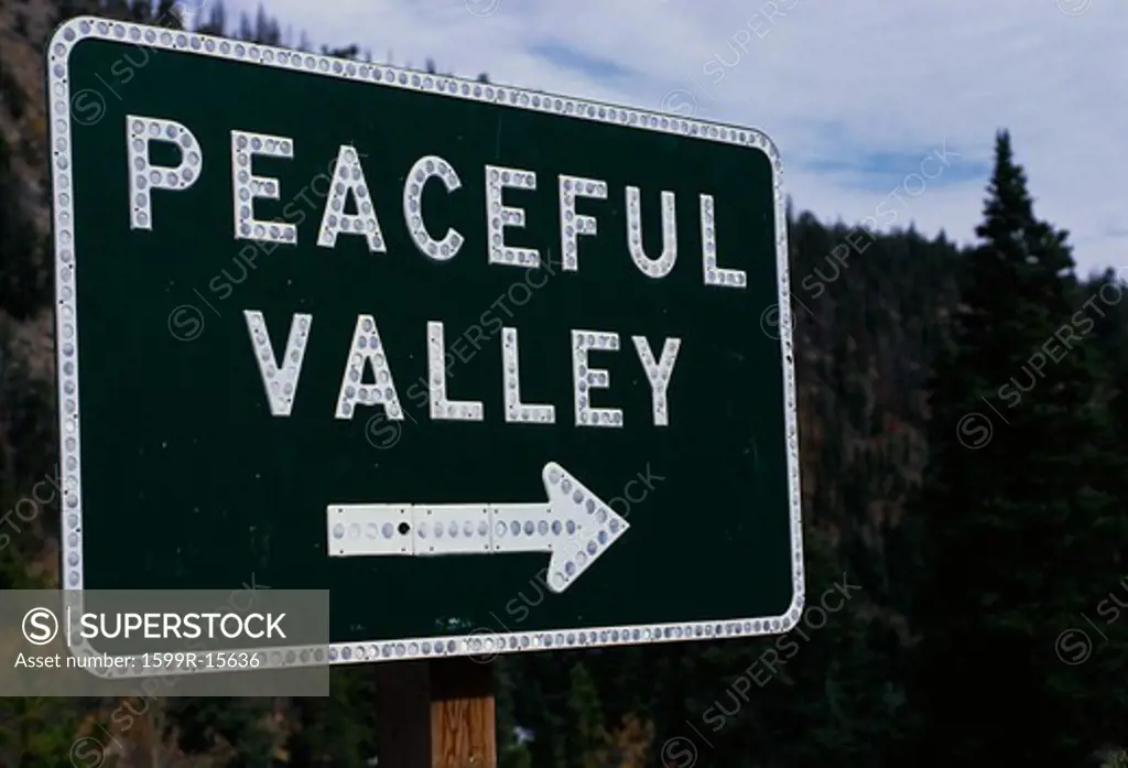 This is a road signs that says Peaceful Valley. There is white arrow pointing the way beneath the lettering.