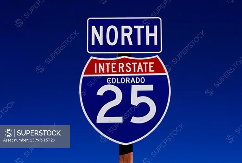 This is a road sign indicating the road is Interstate 25 going north. The sign is blue, red and white against a blue sky.