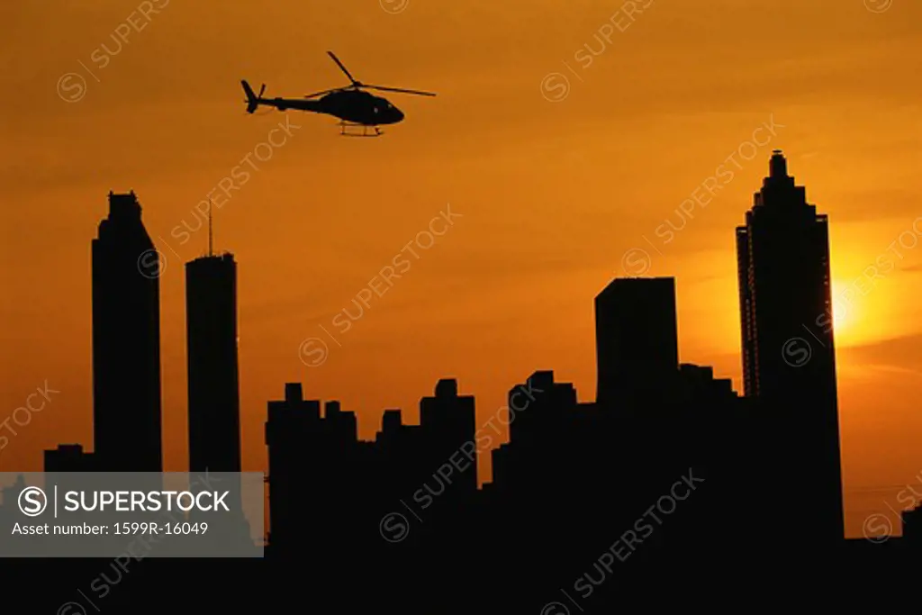Helicopter flying over Atlanta skyline at sunset