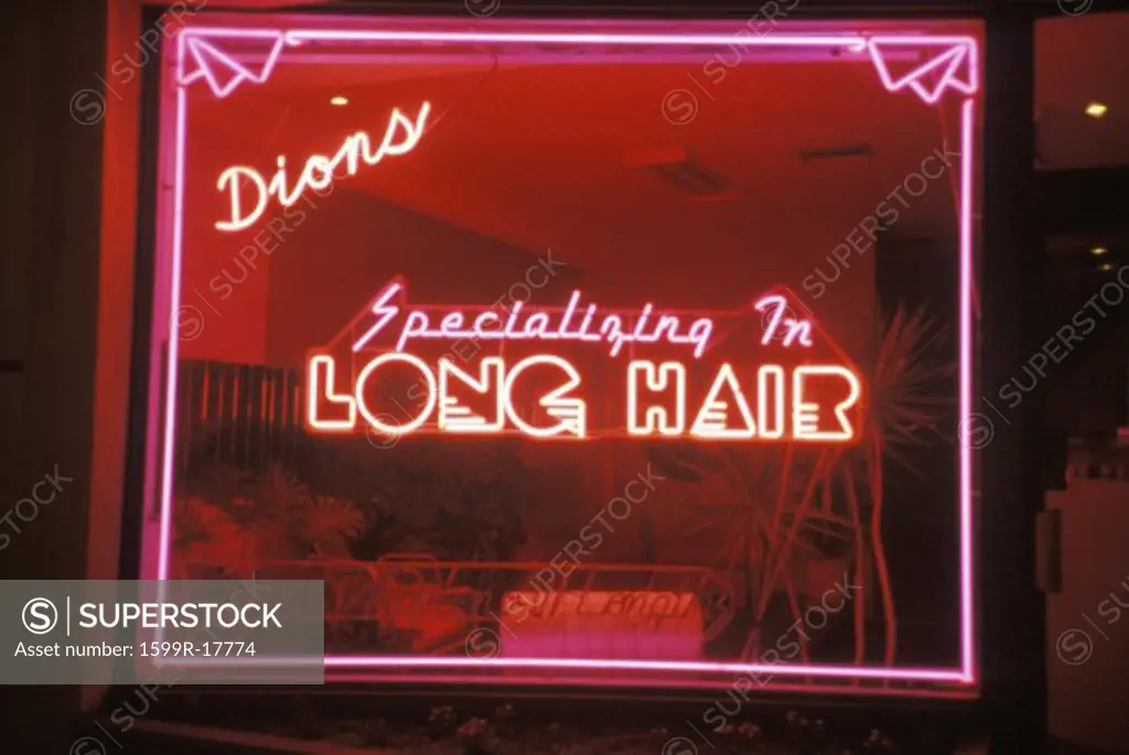 A neon sign that reads Dions, specializing in long hair