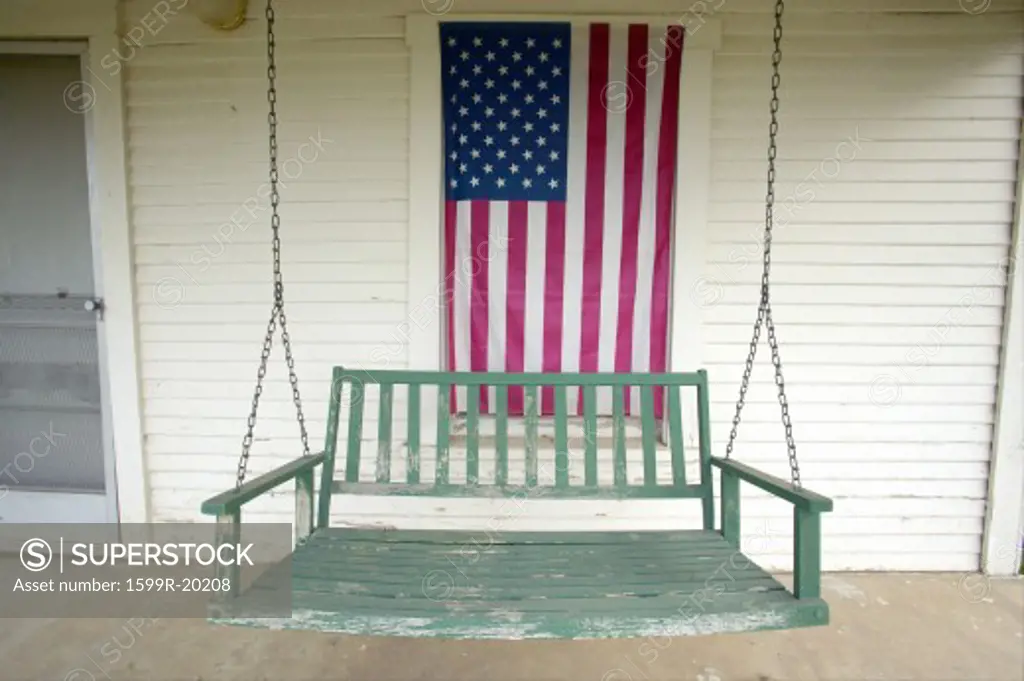 Old swing on porch displaying an American Flag and patriotic theme near Barstow CA off Route 60