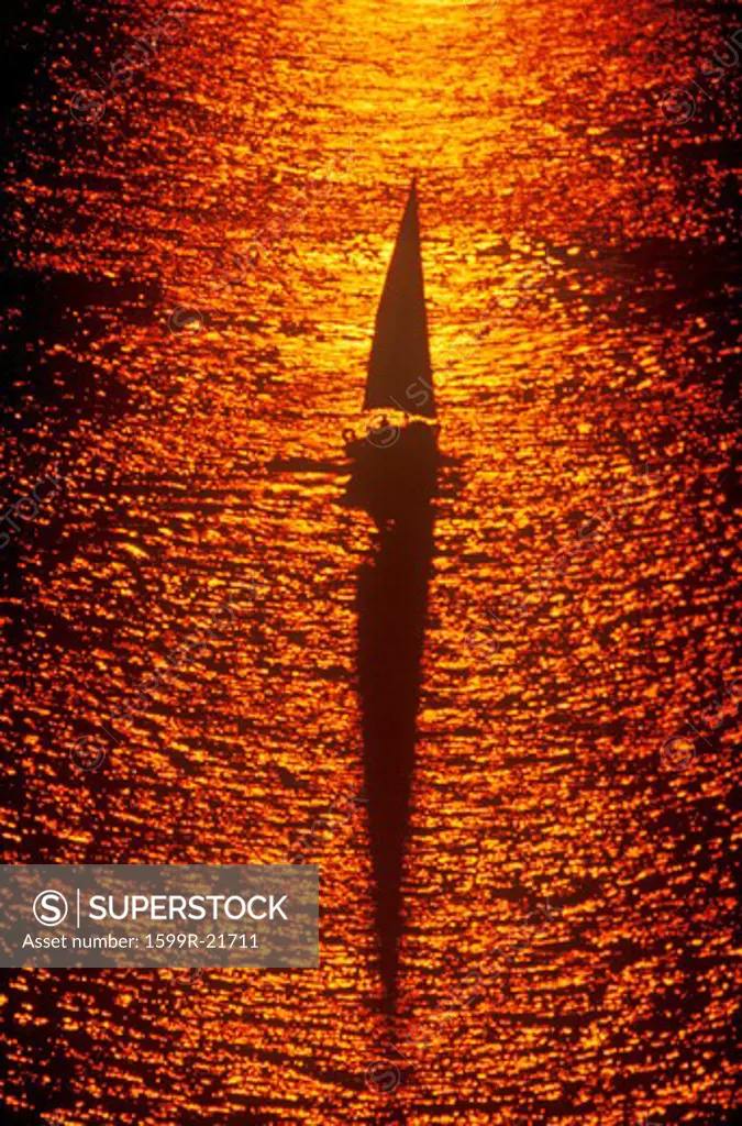 A sailboat cruising during a sunset
