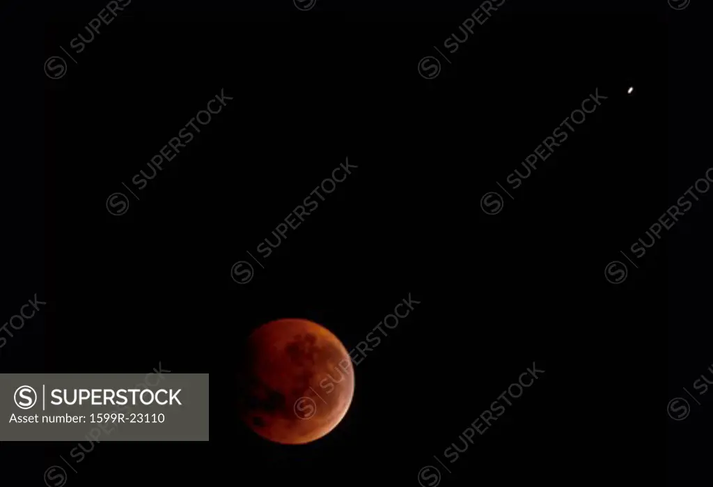 A full moon mostly covered by Earth's shadow during a lunar eclipse against a black starless sky