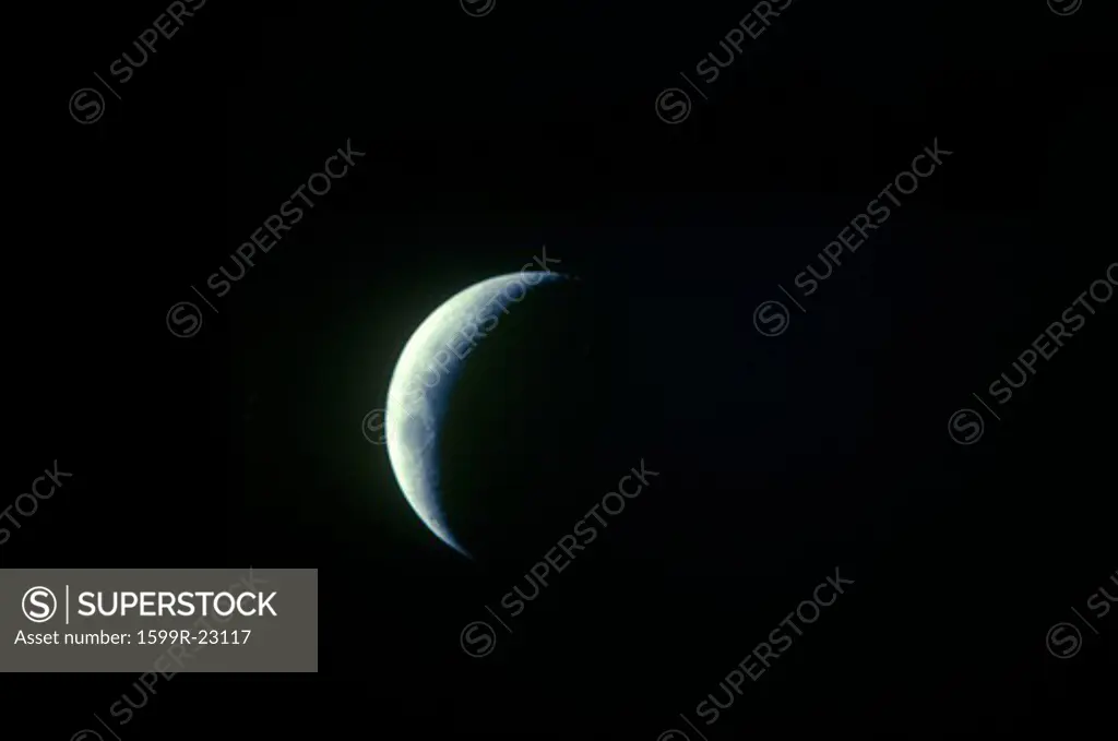A crescent moon against a black starless sky