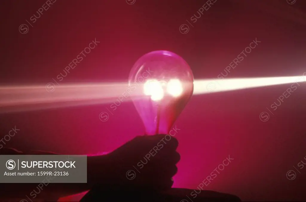 A lightbulb illuminated with a beam of light colors from a laser