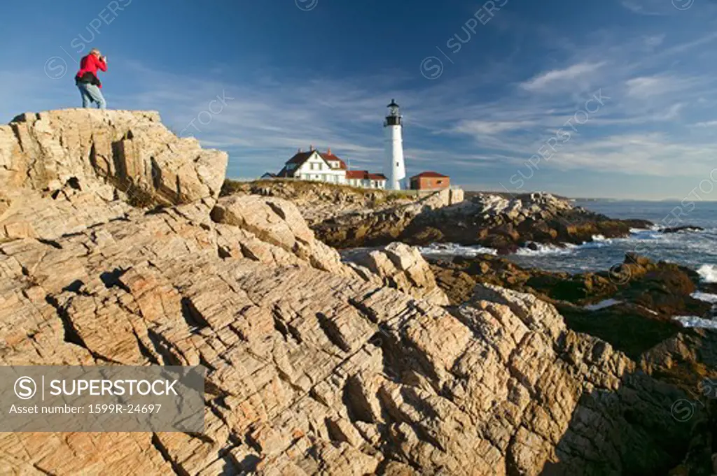 Photographer in red sweatshirt photographs Portland Head Lighthouse, Cape Elizabeth, Maine