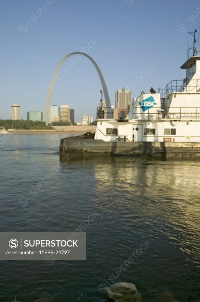 Daytime view of tug boat pushing barge down Mississippi  River in front of Gateway Arch and skyline of St. Louis, Missouri as seen from East St. Louis, Illinois on the Mississippi River