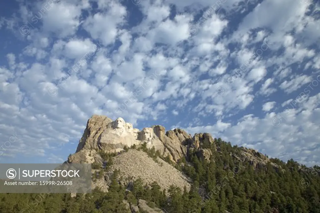 White puffy clouds behind Presidents George Washington, Thomas Jefferson, Teddy Roosevelt and Abraham Lincoln at Mount Rushmore National Memorial, South Dakota