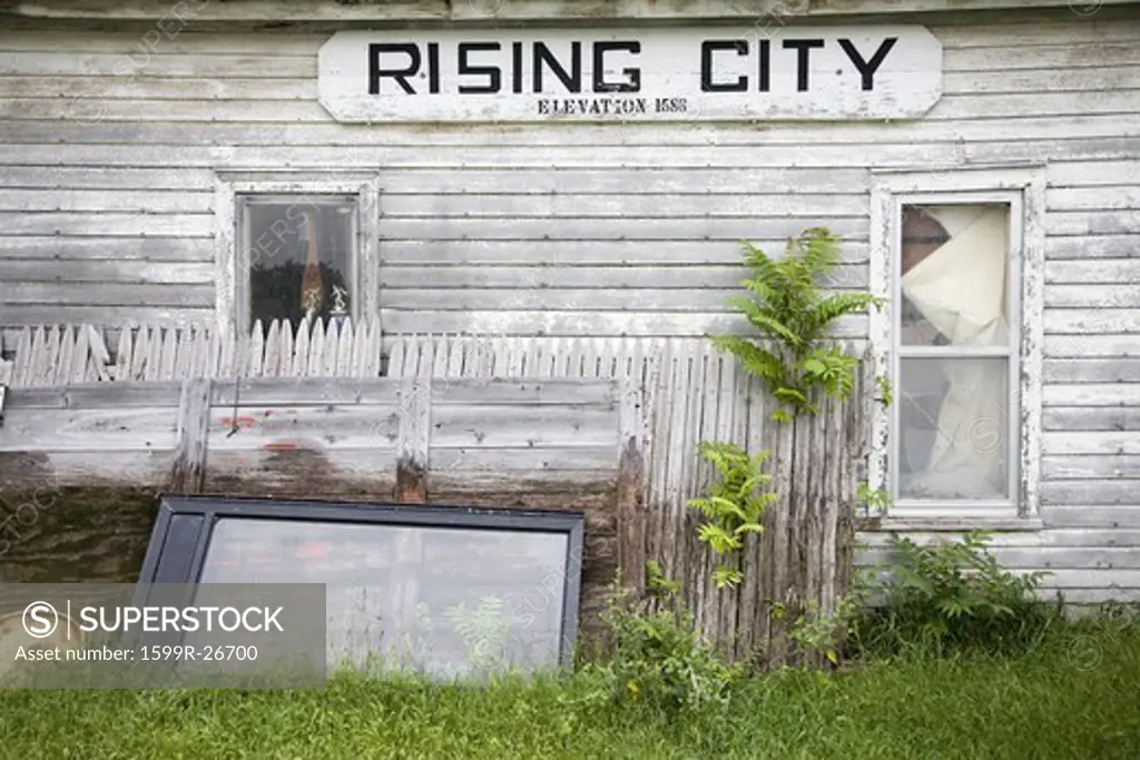A rundown house with a sign on it's side that reads Rising City, Nebraska
