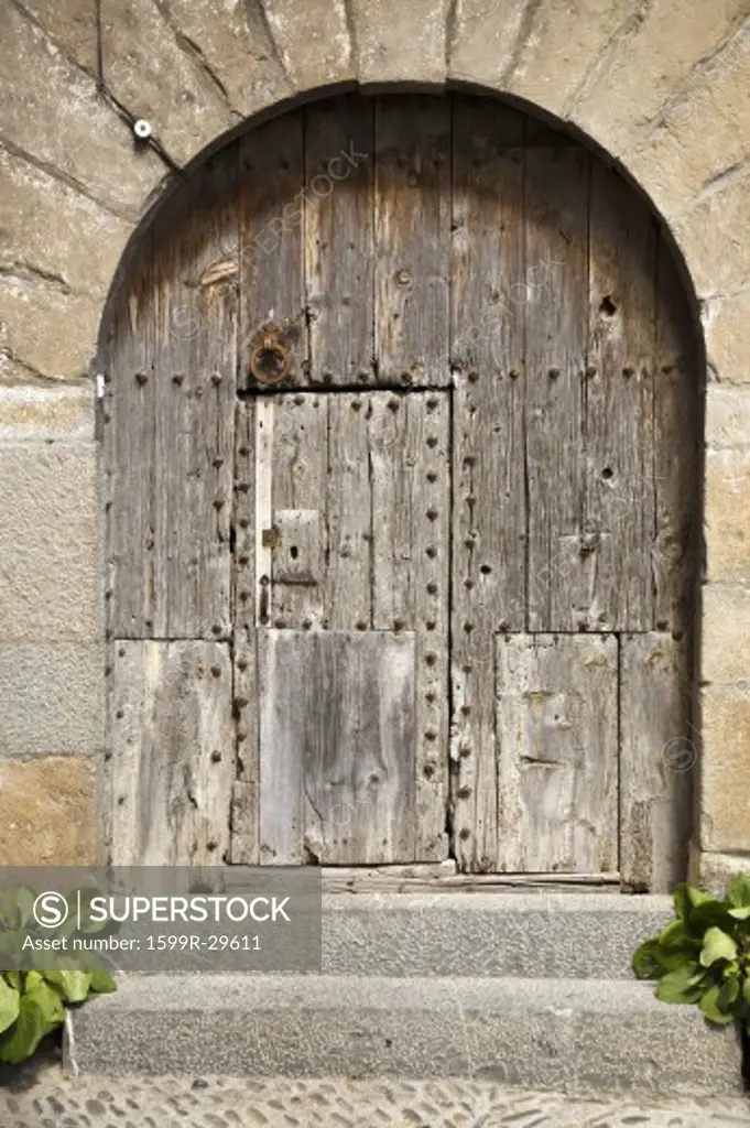 Old arched wooden door on Plaza Mayor, in Ainsa, Huesca, Spain in Pyrenees Mountains, an old walled town with hilltop views of Cinca and Ara Rivers