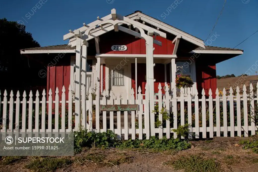 A small red house with White Picket fence, and sign saying 'Private Residence', Harmony, CA, the central coast of California