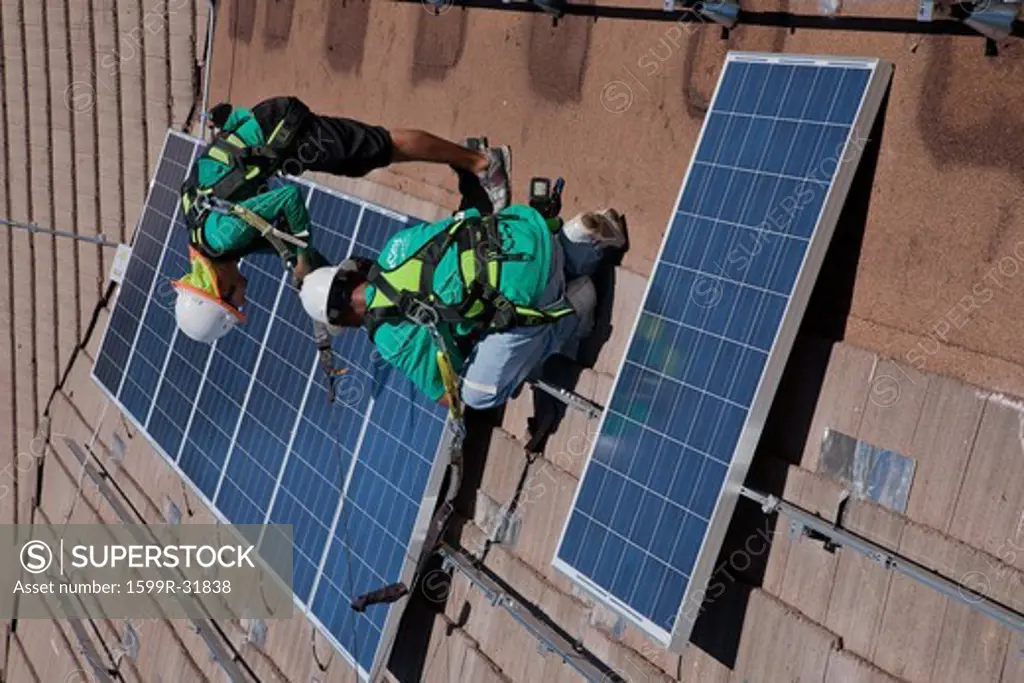 Two male solar workers install solar panels on home in Oak View, Southern California