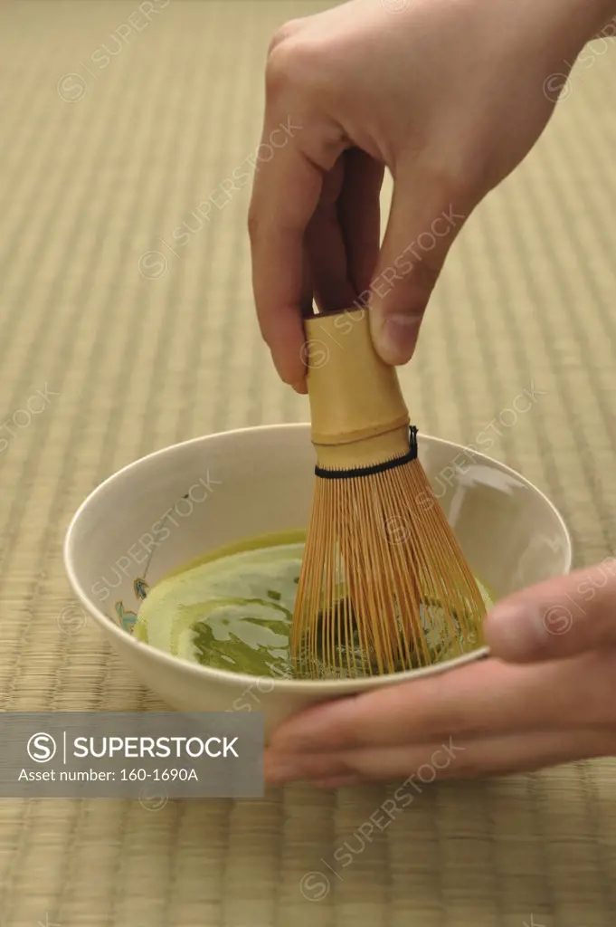 Person using a bamboo whisk to prepare Maccha tea