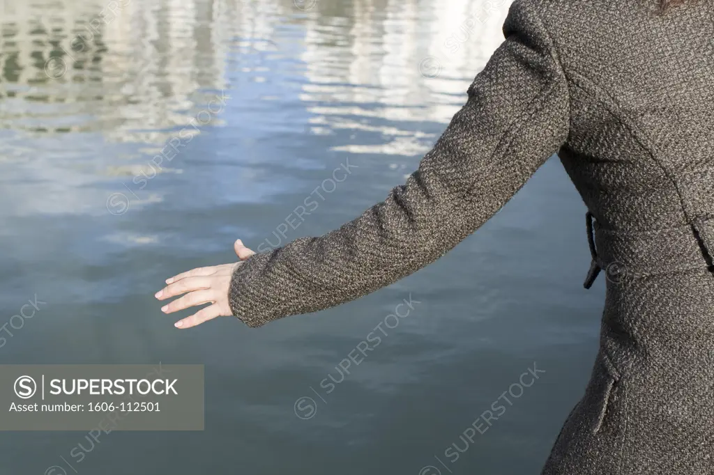Woman wearing a coat, in front of a canal, rear view