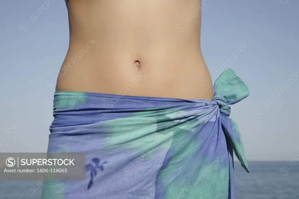 Woman with pareo, close-up of flat belly