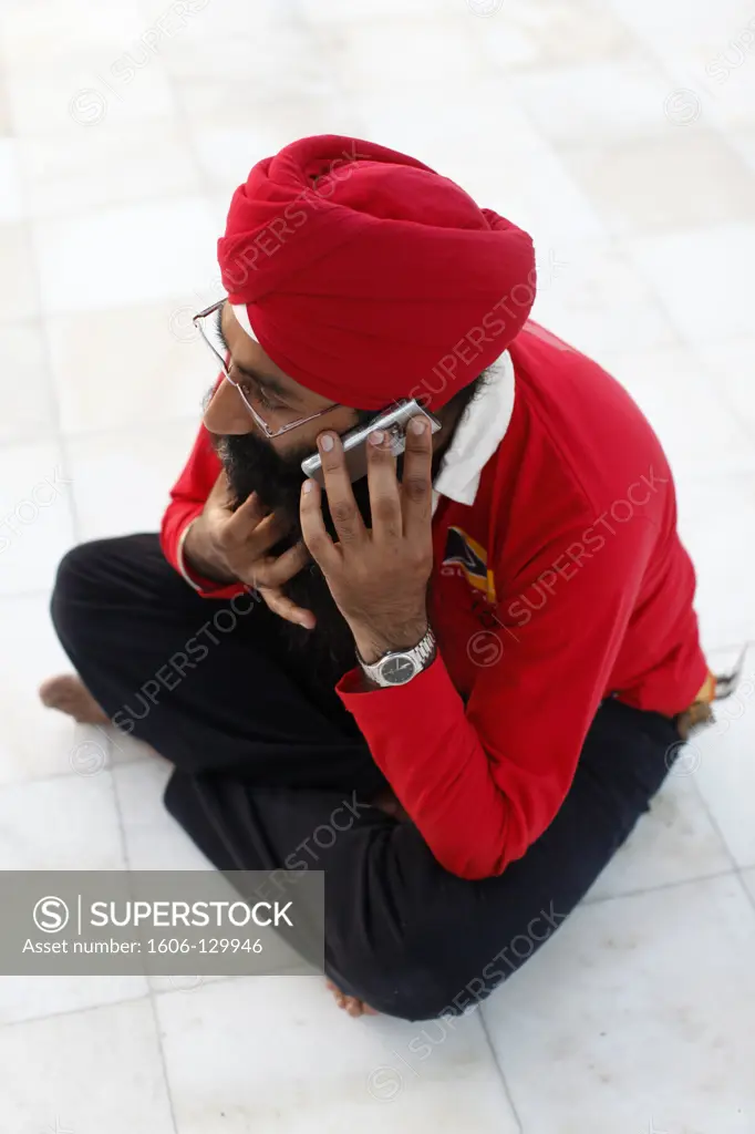 India, Delhi. Sikh using cell phone in Bangla Sahib Gurdwara, New Delhi India.