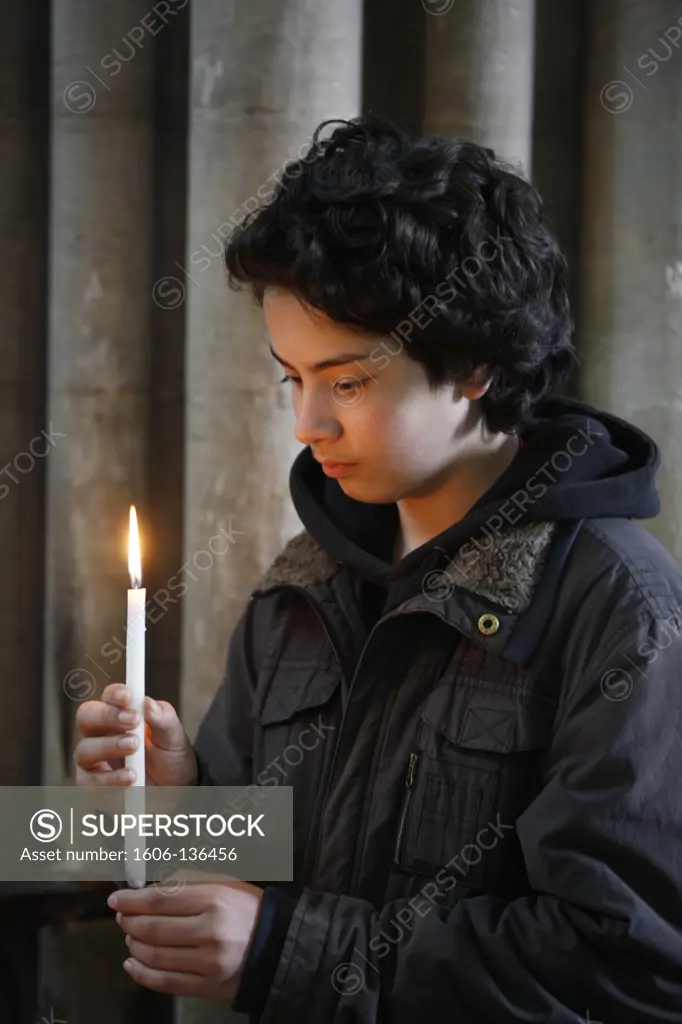 France, Calvados, Bayeux. Teenager holding a candle in Notre Dame de Bayeux cathedral France