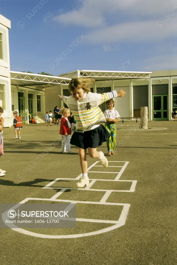 Little girl playing hopscotch in playground