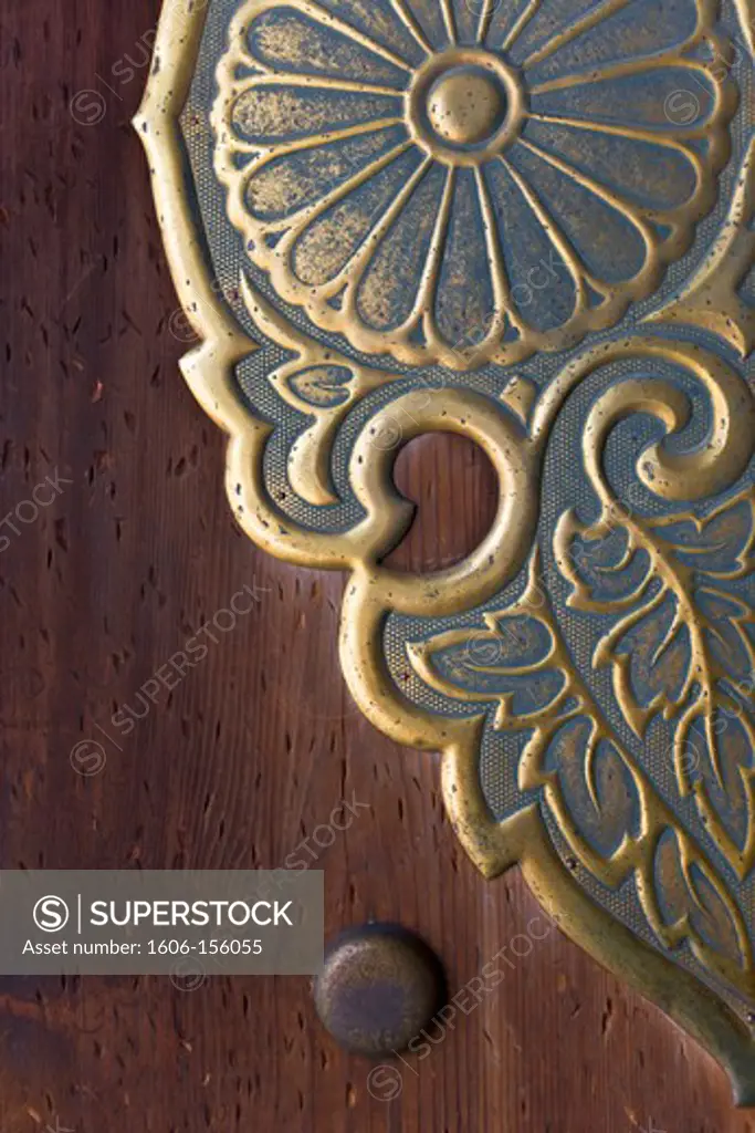 A detailed view reveals the fine craftsmanship in a wooden door with decorative metalwork at the Outer Shrine of Meiji-Jingu Shrine, located in the Shibuya district of Tokyo, Japan. The scars in the door were made by coins tossed by New Year's visitors t