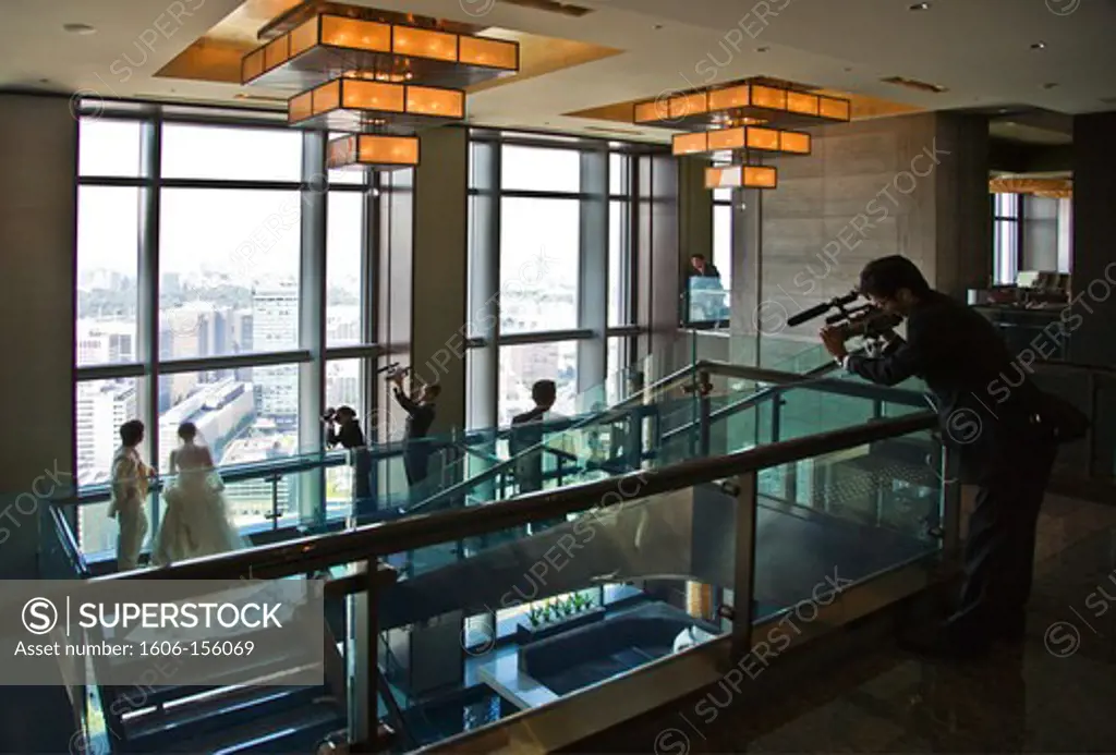 A young Japanese couple pose for wedding photos in the spacious lobby of the Mandarin Oriental Tokyo Hotel atop the Nihonbashi Mitsui Tower, located in the Nihonbashi district of central Tokyo, Japan.