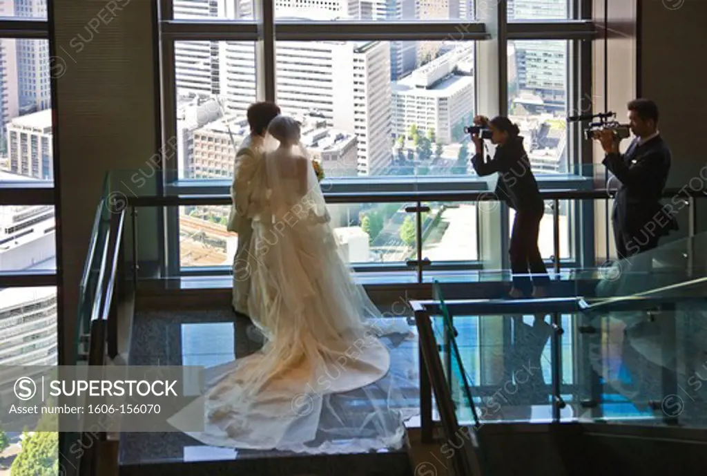A young Japanese couple pose for wedding photos in the spacious lobby of the Mandarin Oriental Tokyo Hotel atop the Nihonbashi Mitsui Tower, located in the Nihonbashi district of central Tokyo, Japan.