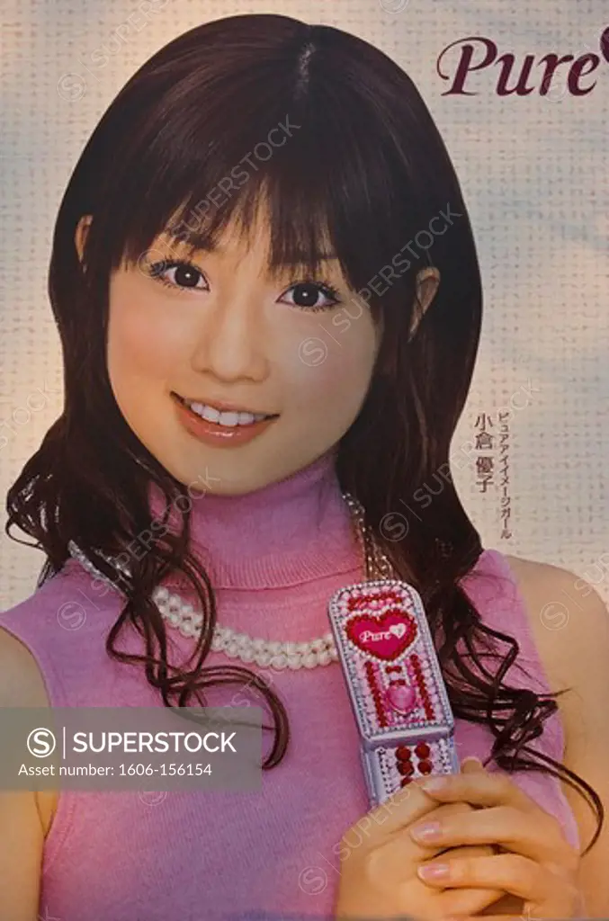 An advertisement on the side of a truck features a smiling and innocent-looking Japanese girl dressed in pink holding a cutely decorated cellphone, and the word, Pure, in the trendy Harajuku District of Tokyo, Japan.