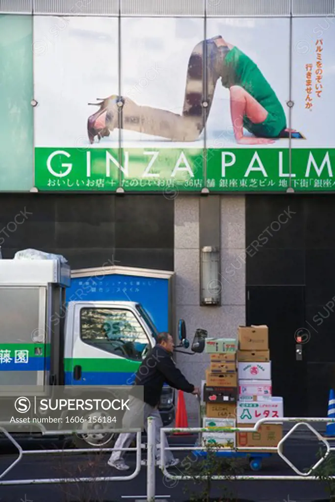 A vendor makes a delivery beneath an amusing advertisement in the Ginza District of Tokyo, Japan.