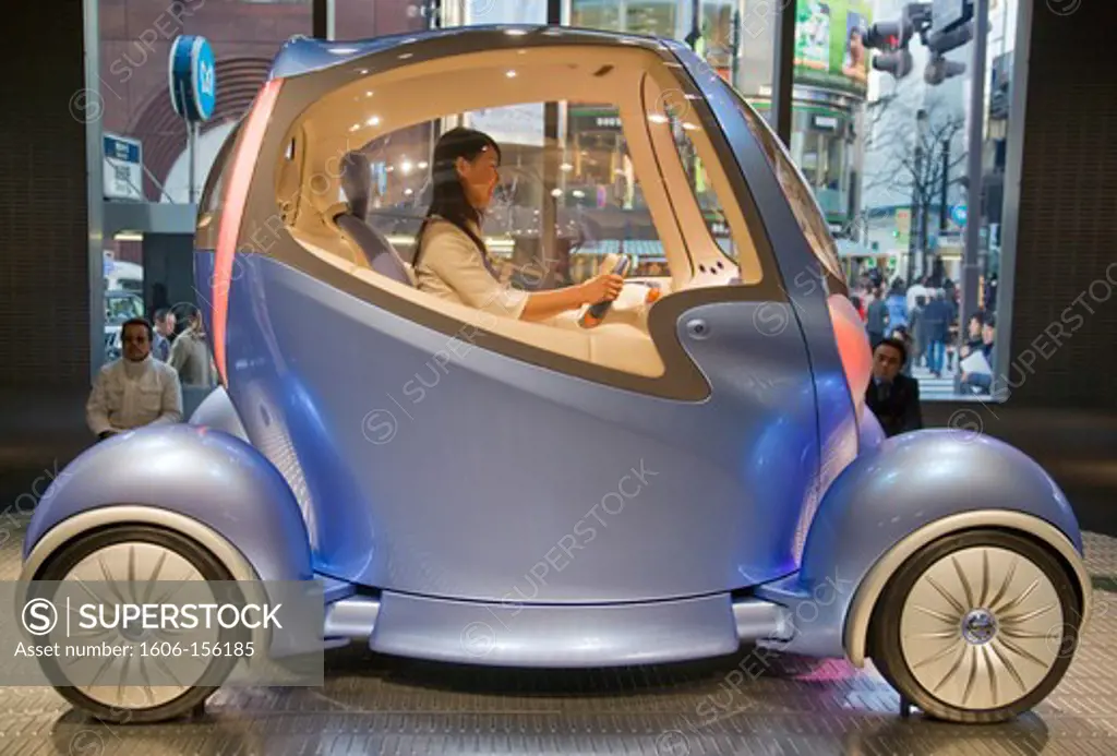 A young female staff member at the Nissan Auto Showroom demonstrates a futuristic prototype electric commuter vehicle in the center of the Ginza District in Tokyo, Japan.