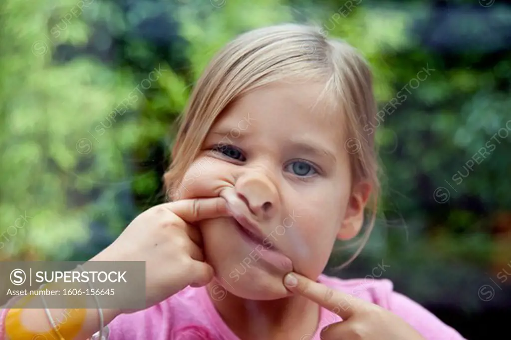 Girl making a grimace, and sticks her face against a window