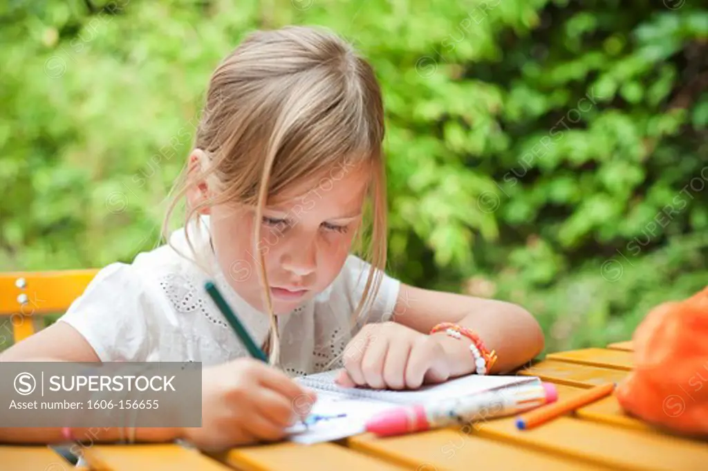 Little girl sitting at a table, drawing