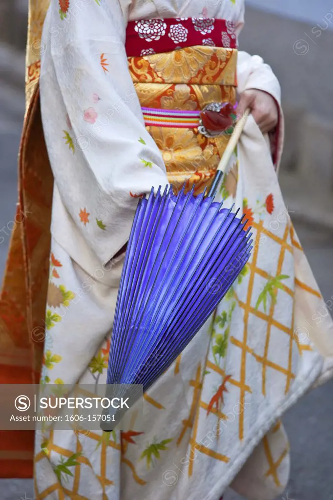 A maiko geisha opens a traditional paper umbrella in the Kitano district of Kyoto, Japan.