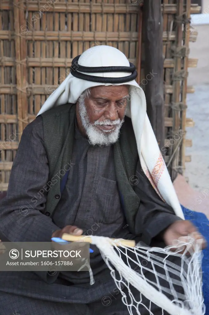 United Arab Emirates, Dubai, old man mending fishing nets,