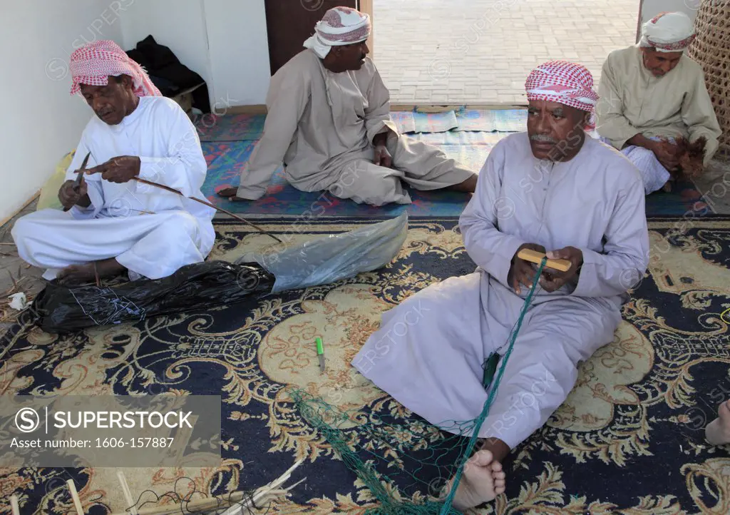 United Arab Emirates, Dubai, old men mending fishing nets,