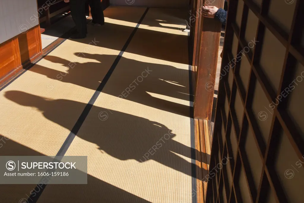 Visitors walking along a veranda cast graphic shadows on tatami mats inside the Shoin main building of the Omuro Gosho Old Imperial Palace at Ninnaji Temple, a World Heritage Site located in the northern area of Kyoto, Japan.