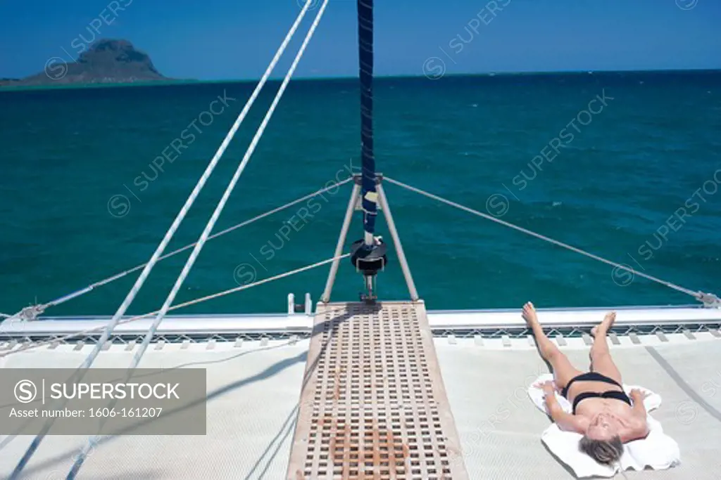 Woman with a swimsuit getting a tan on catamaran's trampoline, Mauritius, Indian Ocean