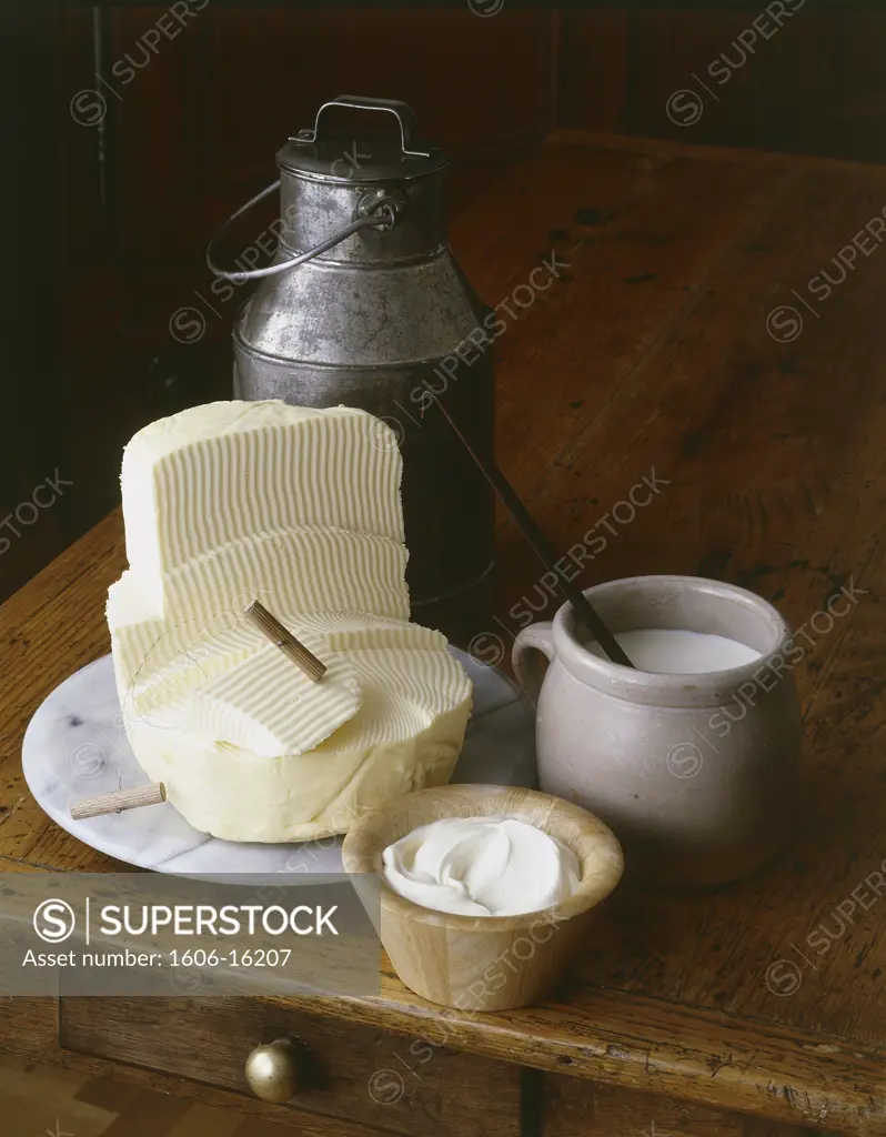 Milk products: lump of butter, cream jug, milk jug, wooden table, indoors