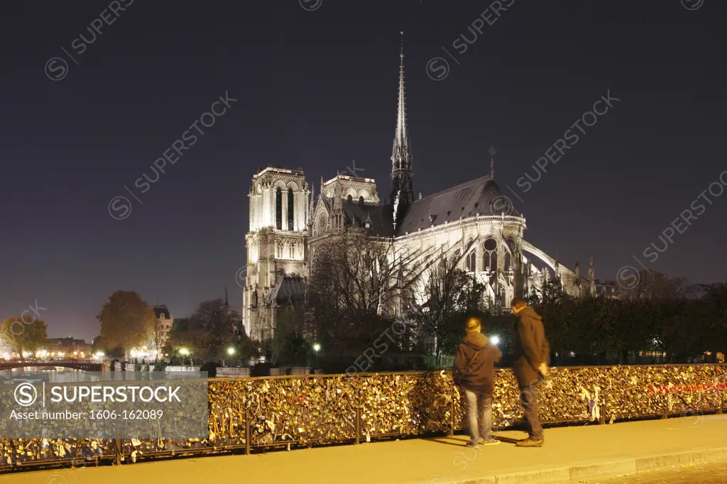 France,Paris,4th, Ile de la Cité,the cathedral Notre Dame and la Seine at night, tourist looking the padlocks of love at the Archevêché Bridge