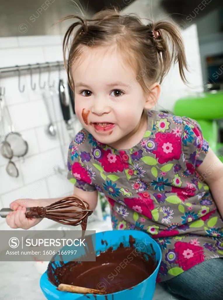 Little girl playing with chocolate in the kitchen
