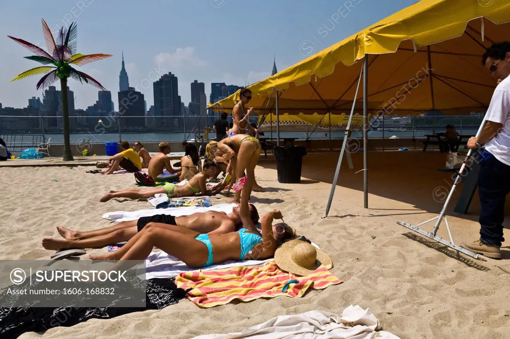 New York - United States, people sunbathing on a fake beach at Harry's, Water Taxi Beach, bar, beach, volley at Long Island city in front of Midtown Manhattan