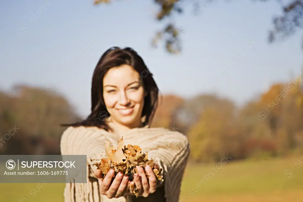 Portrait of a woman with leafes in Park smiling at camera