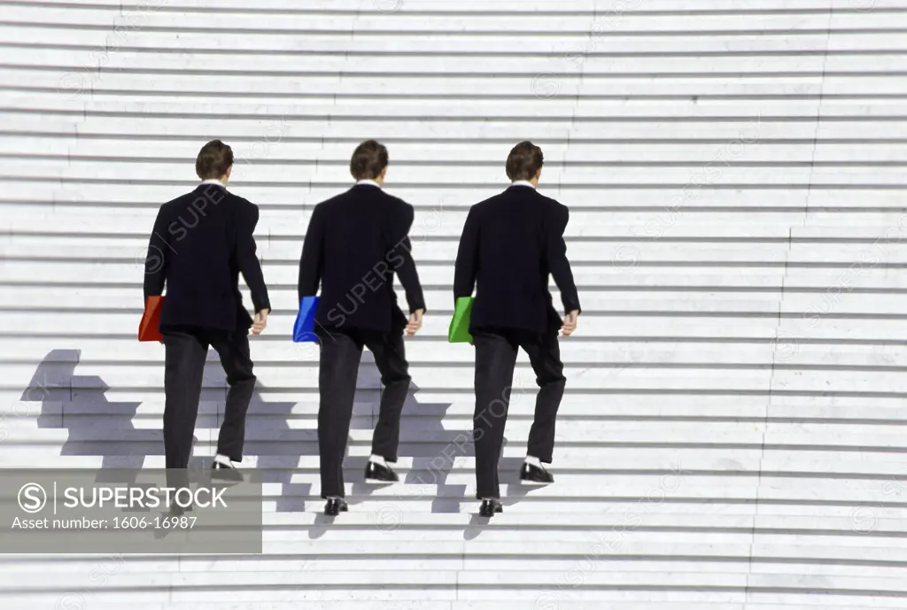 Three businessmen climbing stairs in street, colourful folders
