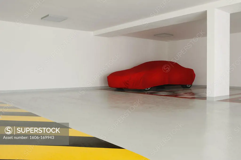 Car in a garage covered with a red tarpaulin
