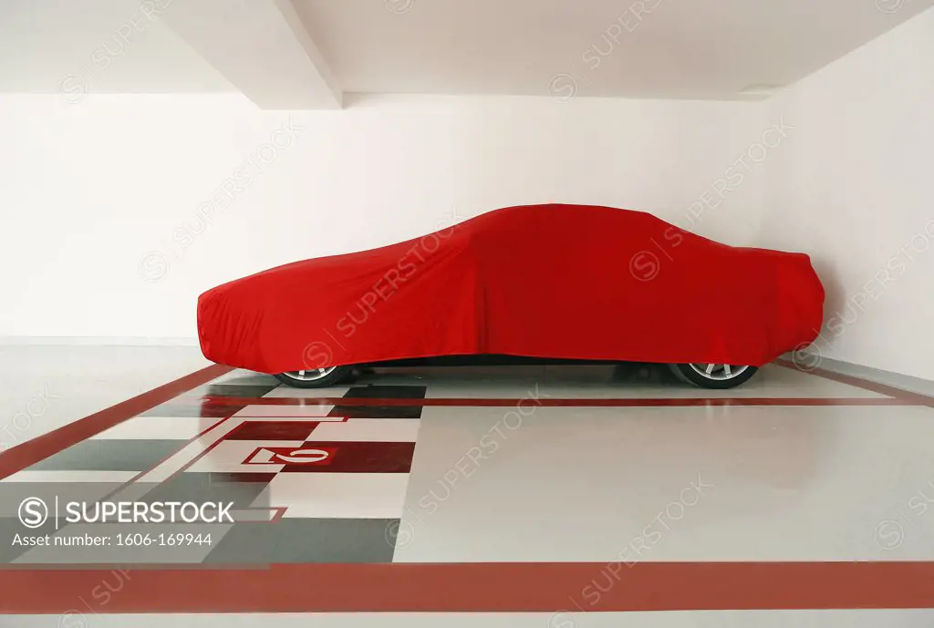Car in a garage covered with a red tarpaulin