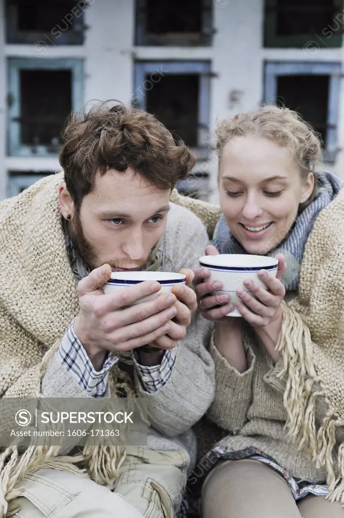 Young couple outside under a blanket with bowls