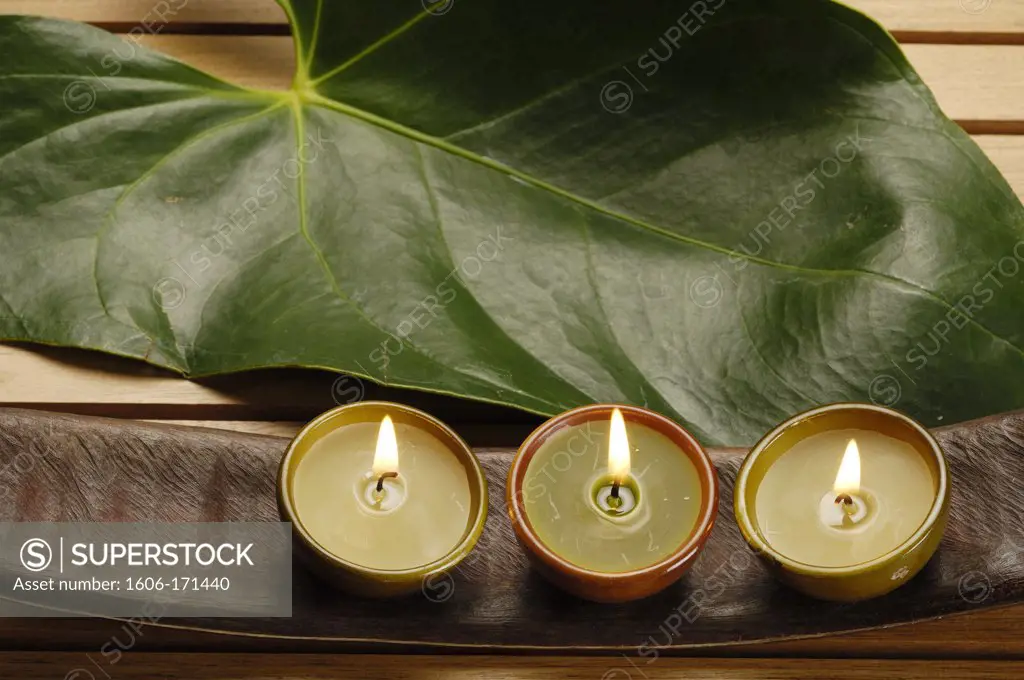 Three lightened candles, leaf and tropical seed