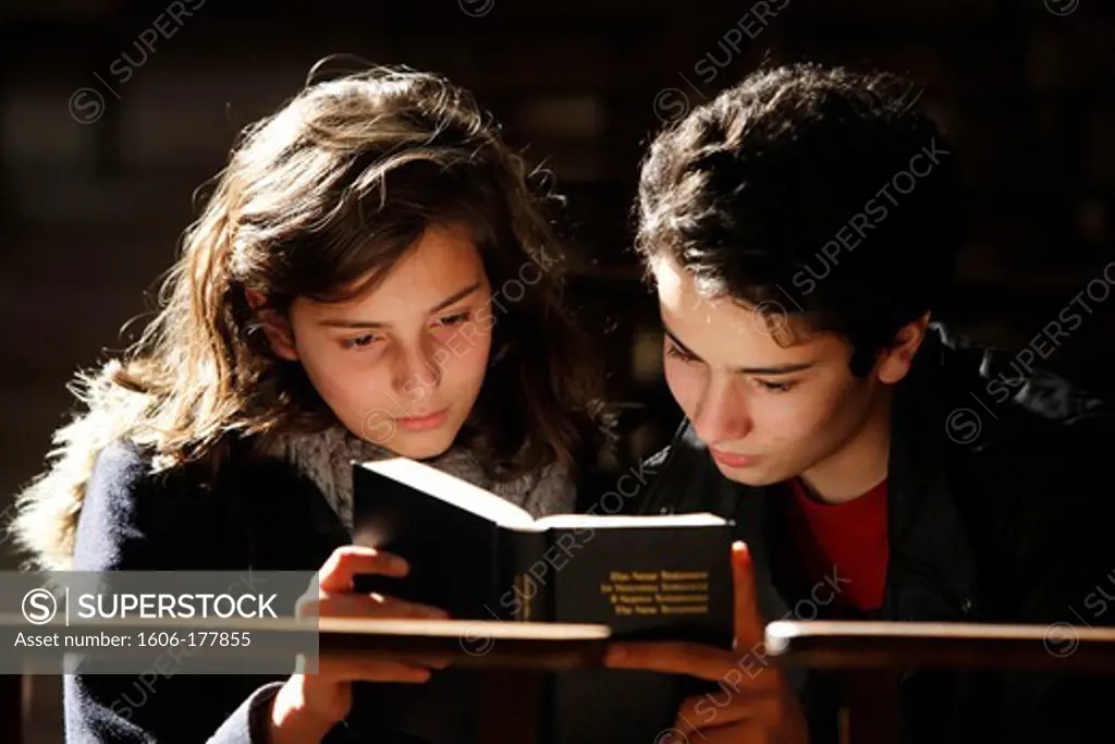 Teenagers reading a bible in Saint Philibert's cathedral, Tournus France.