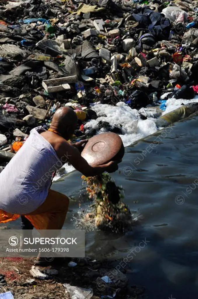 Nepal Kathmandu a monk puts an offering in the middle of the rubish in the sacred BAGMATi river